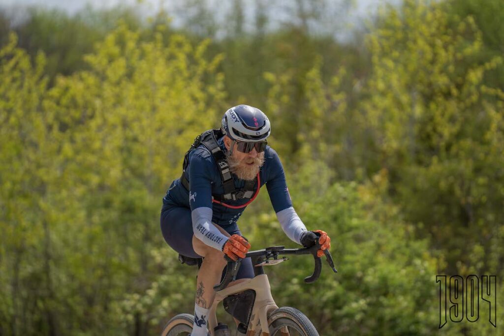 Masters gravel racer riding hard through a spring gravel race